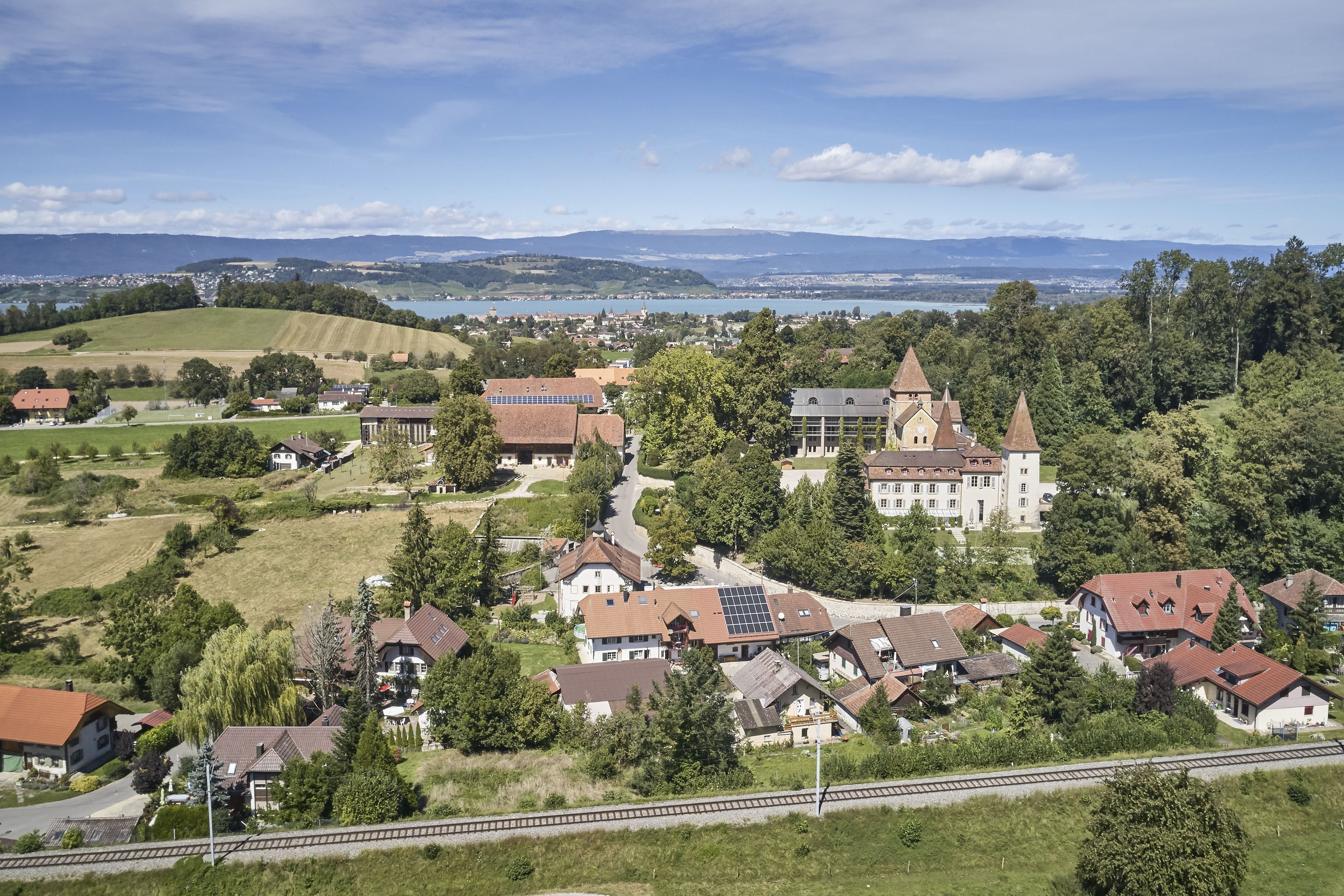 Luftbild Münchenwiler, Ansicht Dorfkern mit Schloss, im Hintergrund der Murtensee